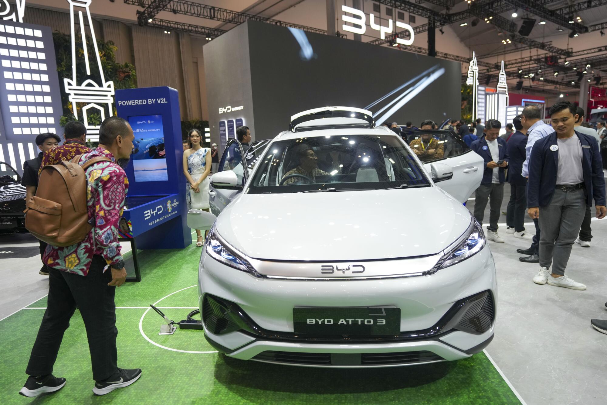 Visitors examine the inside and outside of a BYD ATTO 3 car during an auto show