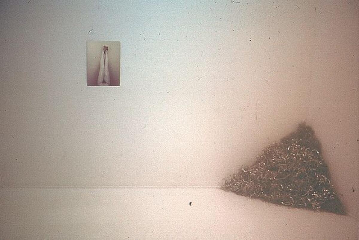 A photograph hangs near a triangle of metal shavings.  