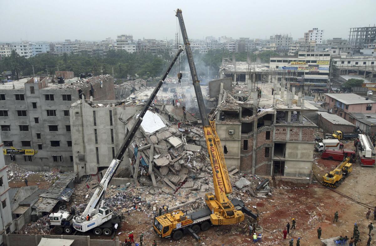 The collapsed Rana Plaza garment factory building is seen from a building nearby as a crane prepares to lift the fallen ceiling in April 2013.