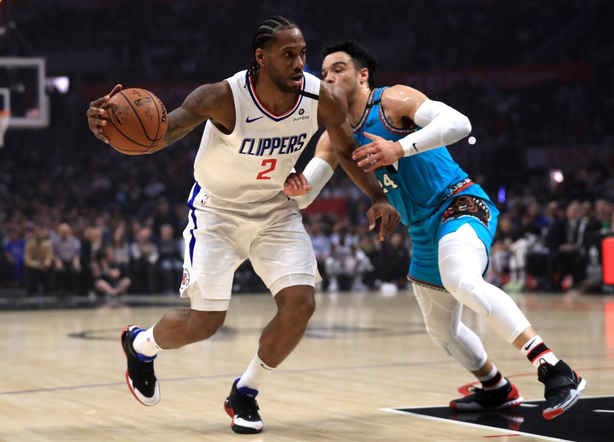 Clippers' Kawhi Leonard (2) dribbles into the defense of Memphis Grizzlies' Dillon Brooks (24) during the first half at Staples Center on Monday.