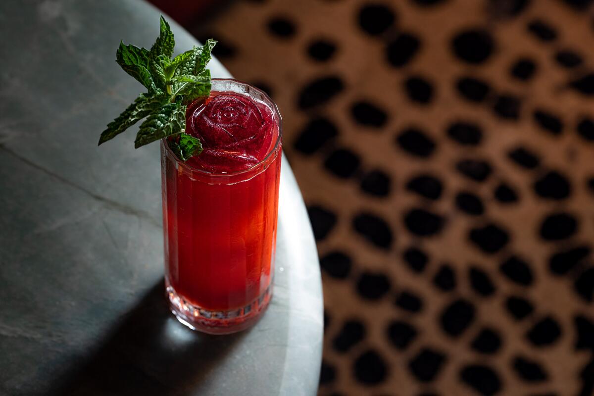 A photo of a magenta cocktail, at whose center floats a rose-shaped ice cube.