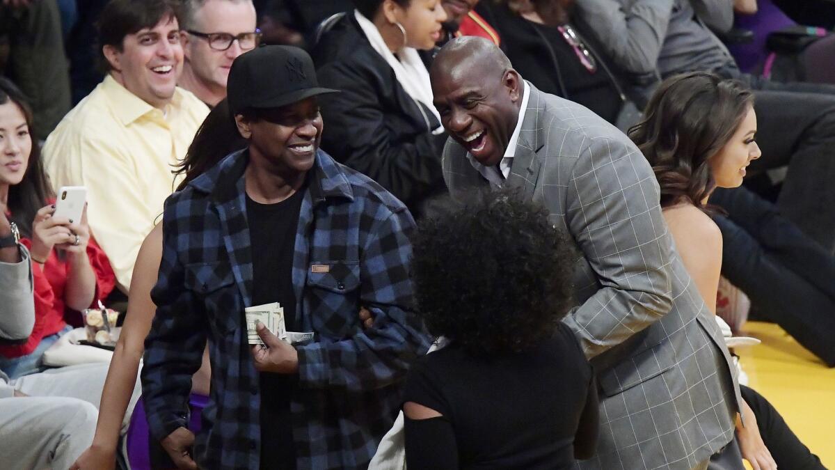 Actor Denzel Washington, left, talks with Magic Johnson, right, and Denzel's wife, Pauletta, during the second half of a game between the Lakers and the Minnesota Timberwolves.