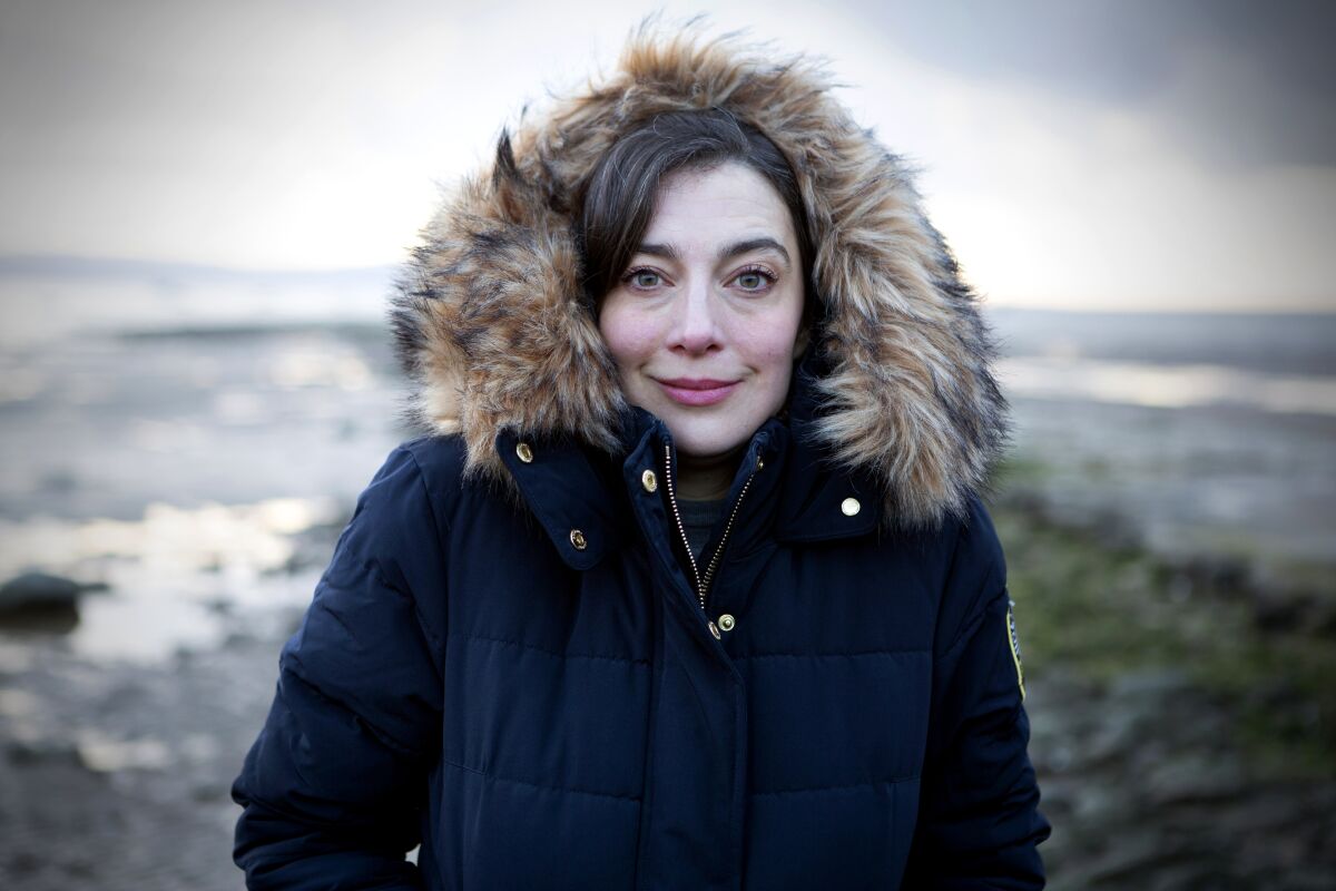 Writer Tabitha Lasley, wearing a parka with a furry hood, on Thurstaton Beach, England. 