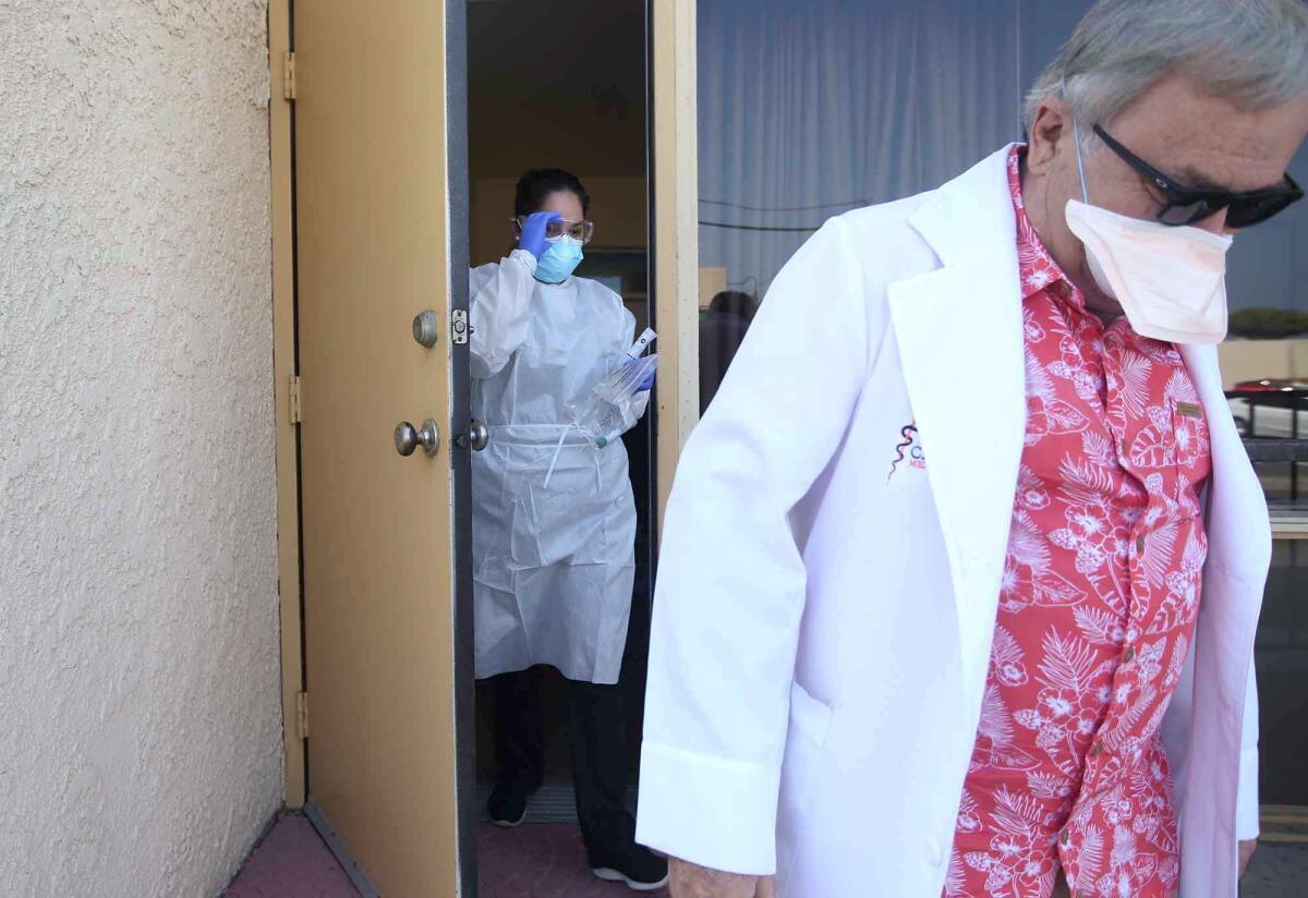 Dr. Gregg DeNicola heads out with assistant Janet Muratalla to administer drive-up coronavirus testing outside the Caduceus Medical Group office on Thalia Street in Laguna Beach.