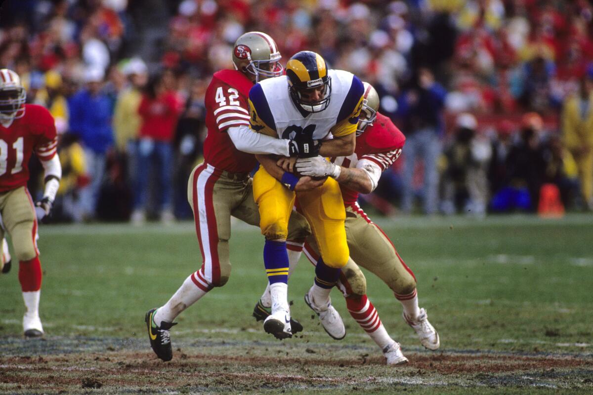 Rams tight end Pete Holohan is brought down by 49ers safety Ronnie Lott (42) and linebacker Michael Walter during the NFC championship game after the 1989 season.