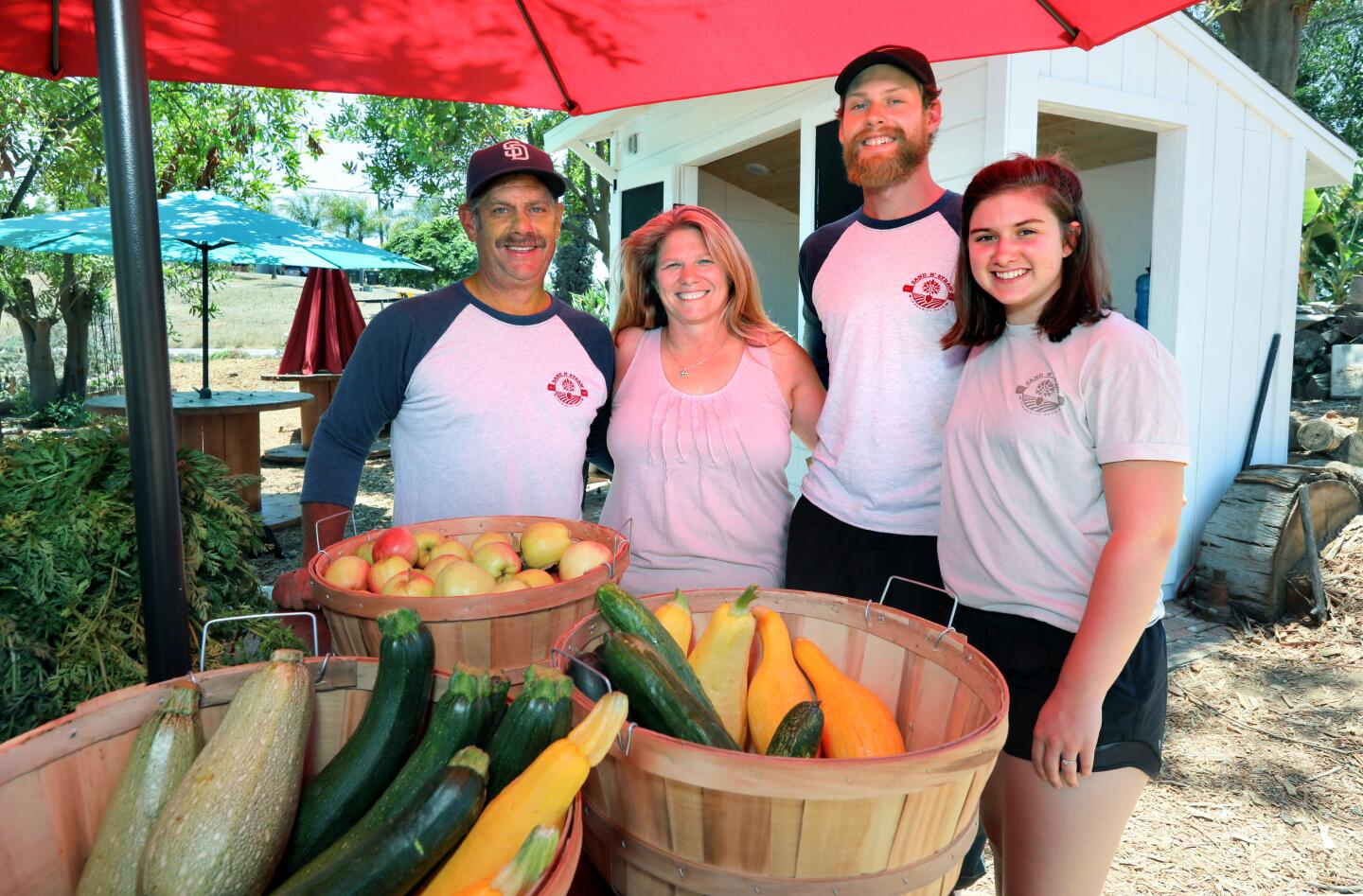 Richard and April Viles, owners of Sand N' Straw Community Farm, at left, with their son Jonathan Viles and his wife Jenna, at right, who help out at the farm. In the foreground are vegetables grown there