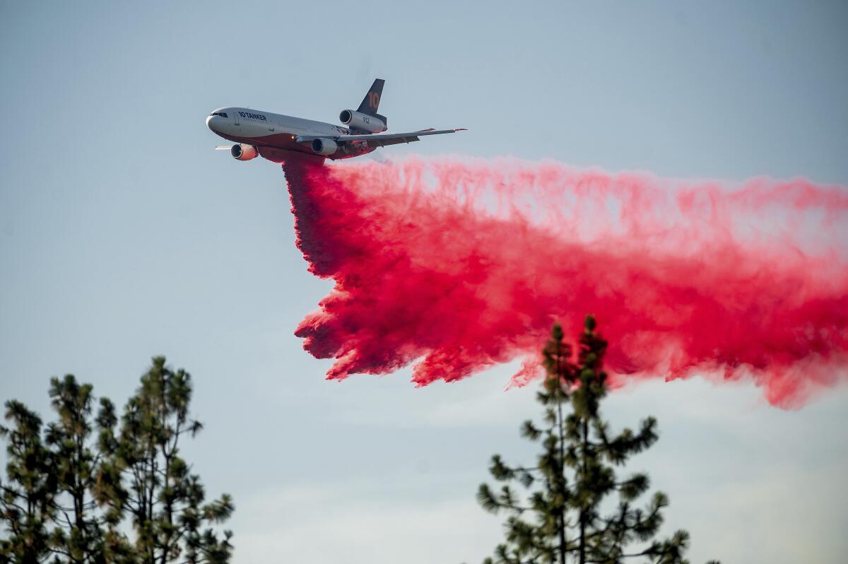 A DC-10 air tanker drops red retardant on a fire. 