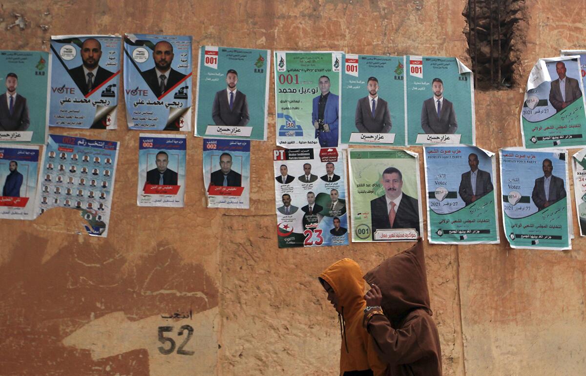 People walk past promotional banners for candidates in the upcoming municipality election in Algiers, Algeria, Thursday, Nov. 25, 2021. (AP Photo/ Fateh Guidoum)