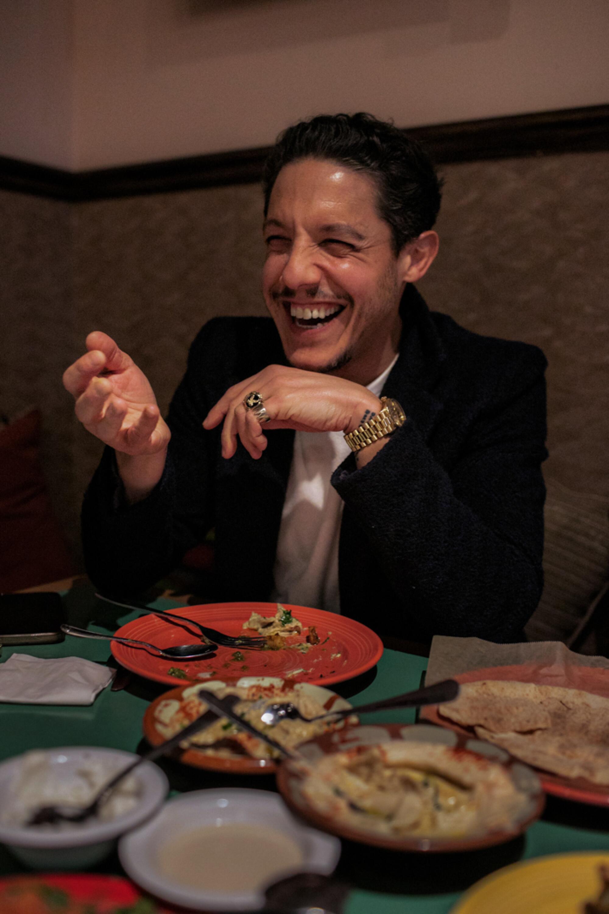 A smiling man enjoys the food at a Lebanese  restaurant.