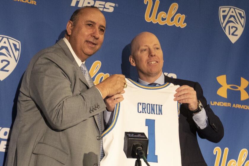 WESTWOOD, CALIF. -- WEDNESDAY, APRIL 10, 2019: UCLA Director of Athletics Dan Guerrero, left, and new UCLA Men?s Head Basketball Coach Mick Cronin, right, hold up a basketball jersey during a press conference in Westwood, Calif., on April 10, 2019. (Brian van der Brug / Los Angeles Times)