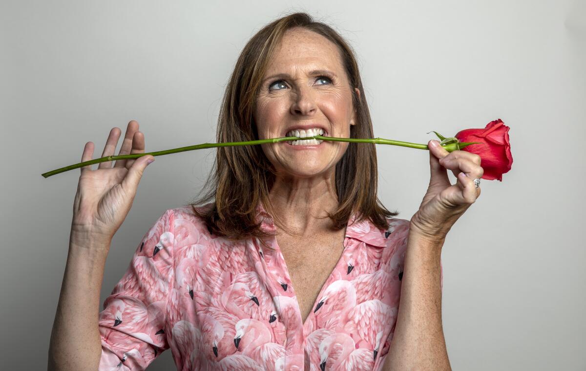Actor Molly Shannon in a flamingo patterned shirt with a rose between her teeth.
