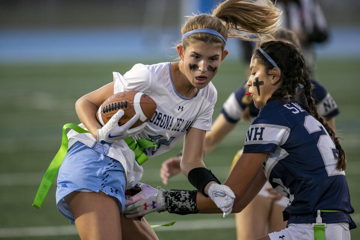 CdM's Mary Kate Angeloff has her flag pulled by Newport Harbor's Maia Helmar during the Battle of the Bay game Wednesday.