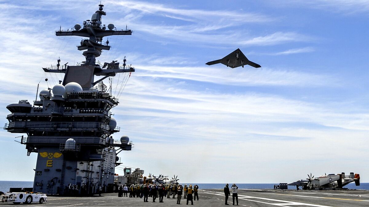 An X-47B Unmanned Combat Air System drone built by Northrop Grumman Corp. flies over the aircraft carrier George H.W. Bush in this undated photo.