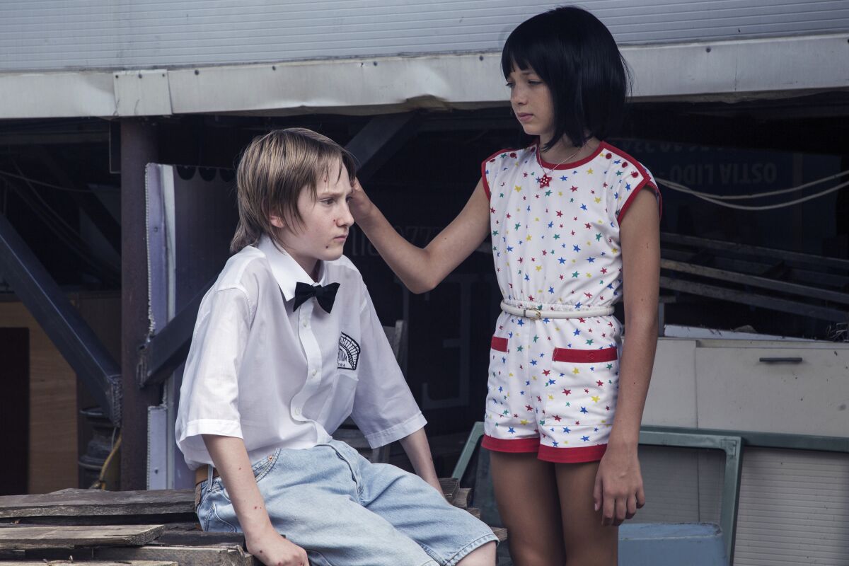 A girl touches the hair of a boy wearing a bow tie