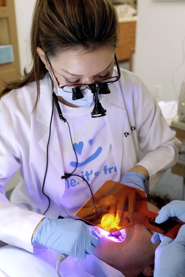 Dr. Karrie Chu uses UV light after doing a filling at Park Place Dental Care's annual Dentistry from the Heart at the Pasadena location on Friday, Sept. 30, 2011. Drs. Robert Shimasaki and Karrie Chu along with two other dentists and their assistants did cleanings, fillings, extractions and root canals for an expected 100 people.