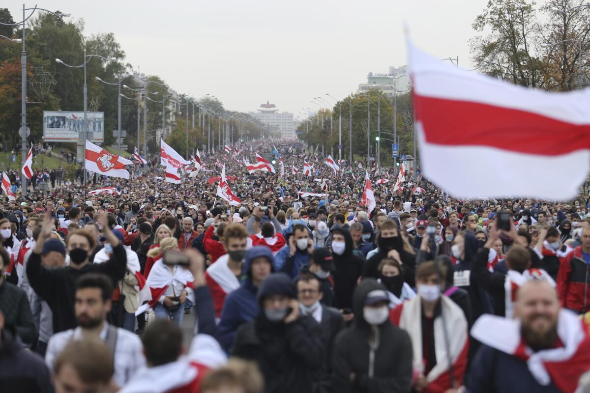 A sea of people with red and white flags fill a street in protest