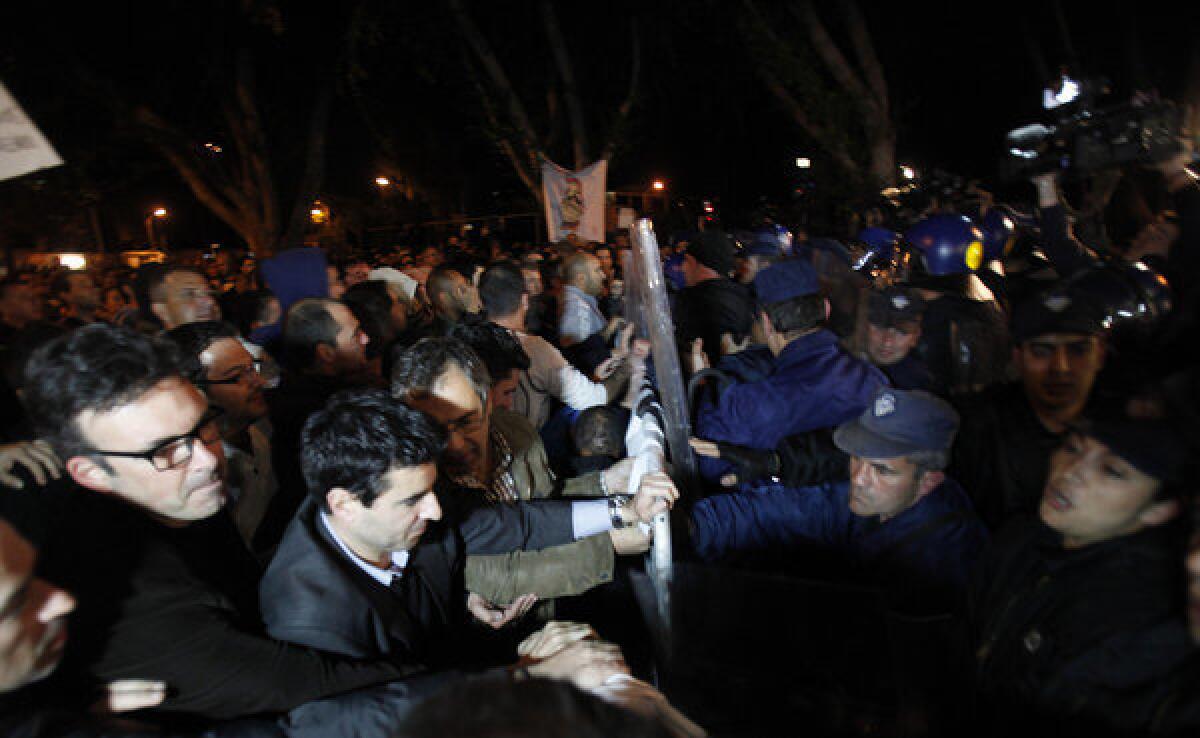 Demonstrators push barriers as riot police try to stop them during a protest outside the Cypriot parliament in Nicosia, Cyprus, Thursday, March 21, 2013.