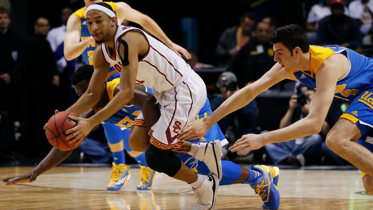 USC guard Jordan McLaughlin, left, grabs a loose ball in front of UCLA's Gyorgy Golomanon on March 9.
