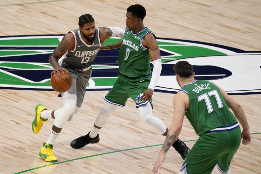 Los Angeles Clippers guard Paul George (13) works to the basket against Dallas Mavericks' Josh Richardson (0) and Luka Doncic (77) during the second half of an NBA basketball game in Dallas, Wednesday, March 17, 2021. (AP Photo/Tony Gutierrez)