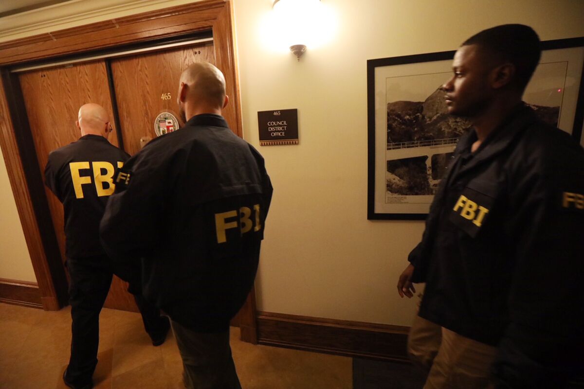 People in "FBI" jackets approach a door.