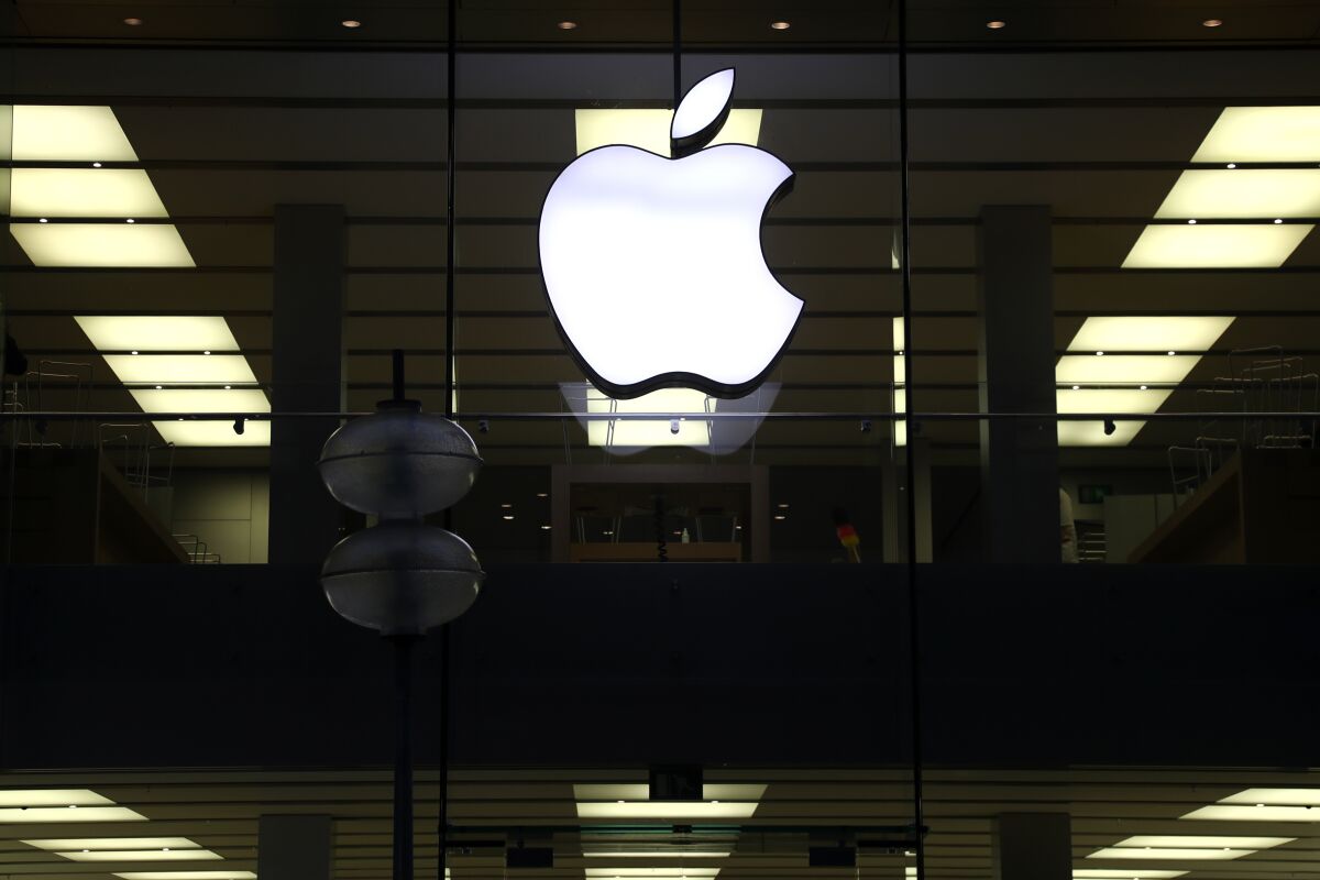 This Dec. 16, 2020 file photo shows an illuminated Apple logo at a store in Munich, Germany. 