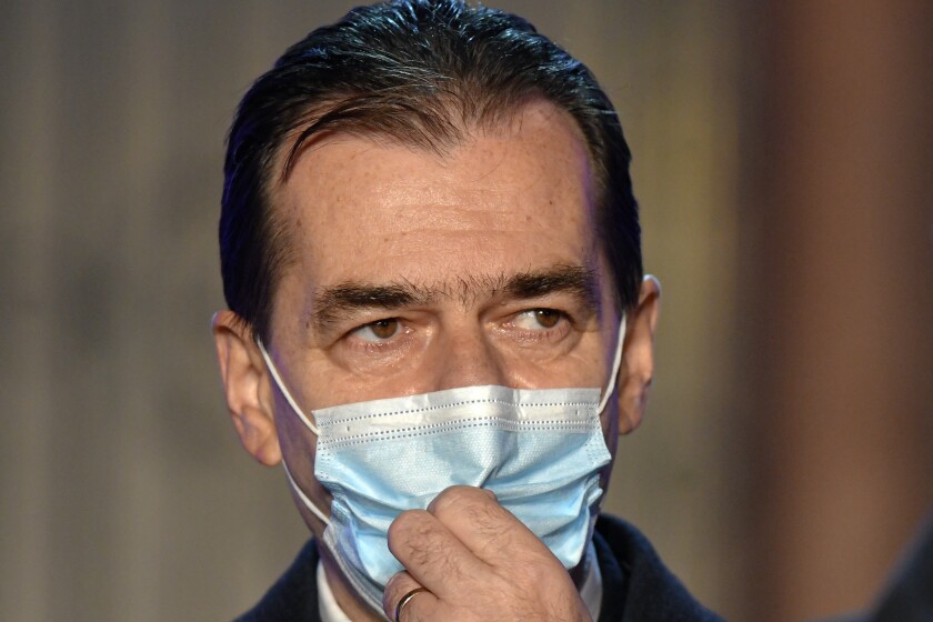 FILE - In this Sunday, Dec. 6, 2020 file photo, Romanian Prime Minister Ludovic Orban and head of the ruling National Liberal party adjusts his mask after exit polls in the country's parliamentary elections were announced, in Bucharest, Romania. Romania’s center-right prime minister Ludovic Orban resigned Monday Dec. 7, 2020, after a general election in which voters delivered nominal victory to the left-leaning, populist opposition party. (AP Photo/Andreea Alexandru, File)
