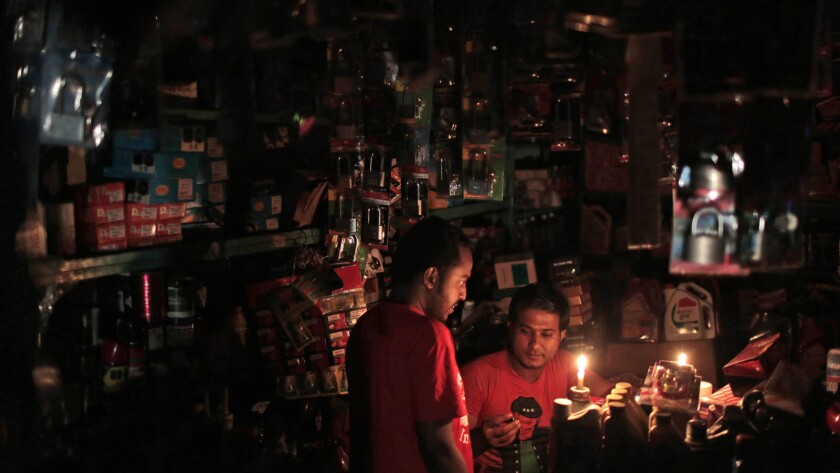 A Bangladeshi salesman interacts with a customer during Saturday's blackout in Dhaka.