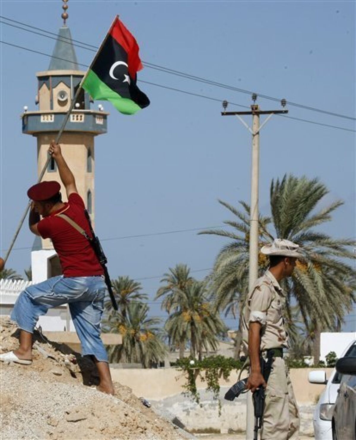 Libyan fighter plants the Libya's flag of the former rebels at a check point in Al Ajaylat, 120 km west of Tripoli, Libya, Wednesday, Sept. 7, 2011. The new colours of the flag decorate a lot of streets and buildings after the six-month civil war that ended Gadhafi's 42-year rule and sent him into hiding. (AP Photo/Francois Mori)