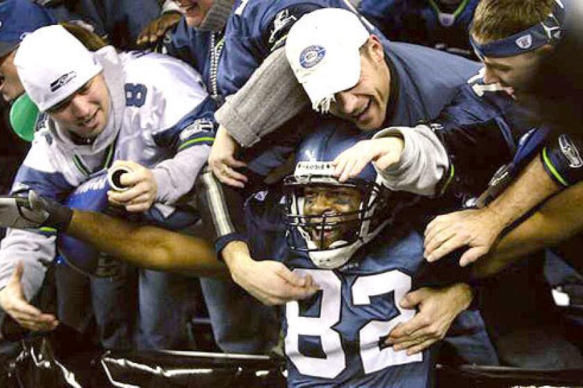 CELEBRATION: Seattle wide receiver Darrell Jackson celebrates with fans in the stands after scoring a touchdown in third quarter.