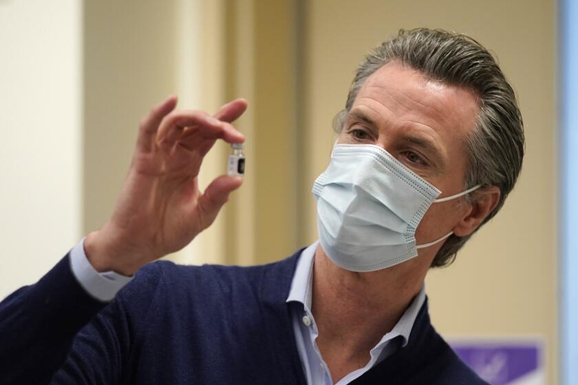 FILE - In this Dec. 14, 2020, file photo, California Gov. Gavin Newsom holds up a vial of the Pfizer-BioNTech COVID-19 vaccine at Kaiser Permanente Los Angeles Medical Center in Los Angeles. With frustration rising over the slow rollout of the vaccine, state leaders and other politicians are turning up the pressure, improvising and seeking to bend the rules to get shots in arms more quickly. (AP Photo/Jae C. Hong, File)