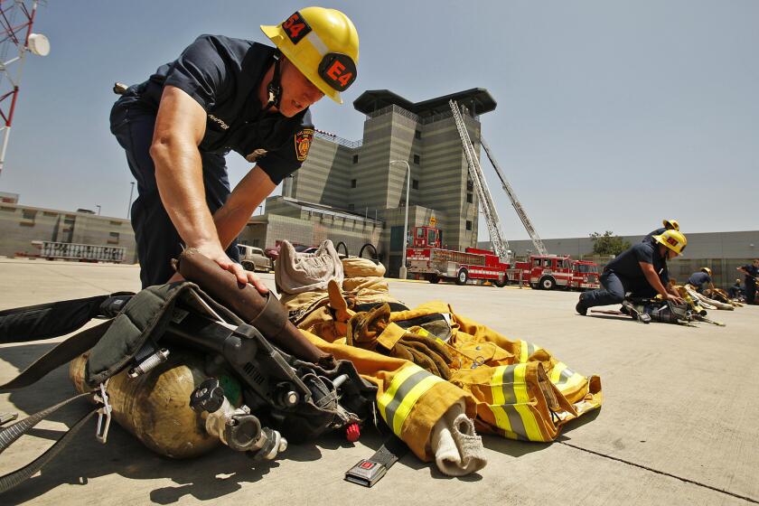 Christopher Napper, one of 70 recruits in the Los Angeles Fire Department class named in January, prepares his equipment for demonstrations during the recruit graduation ceremony in Panorama City.
