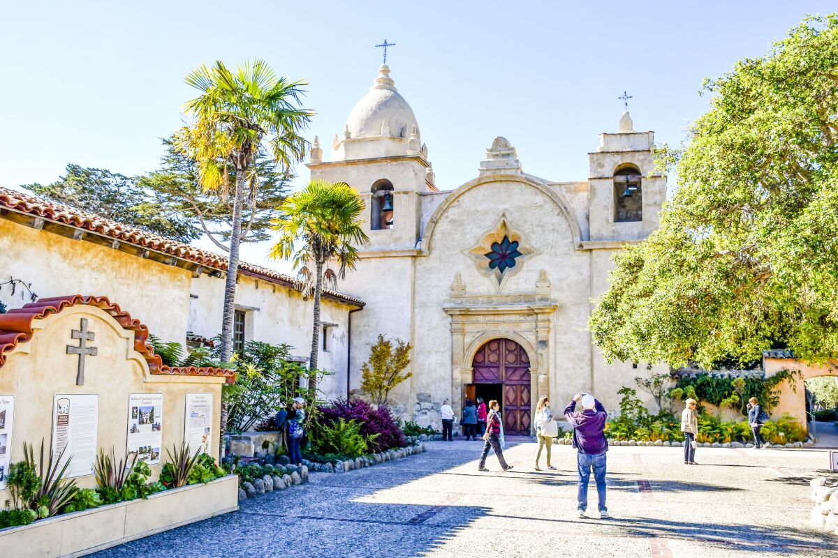 People walk around in the courtyard of Carmel Mission.