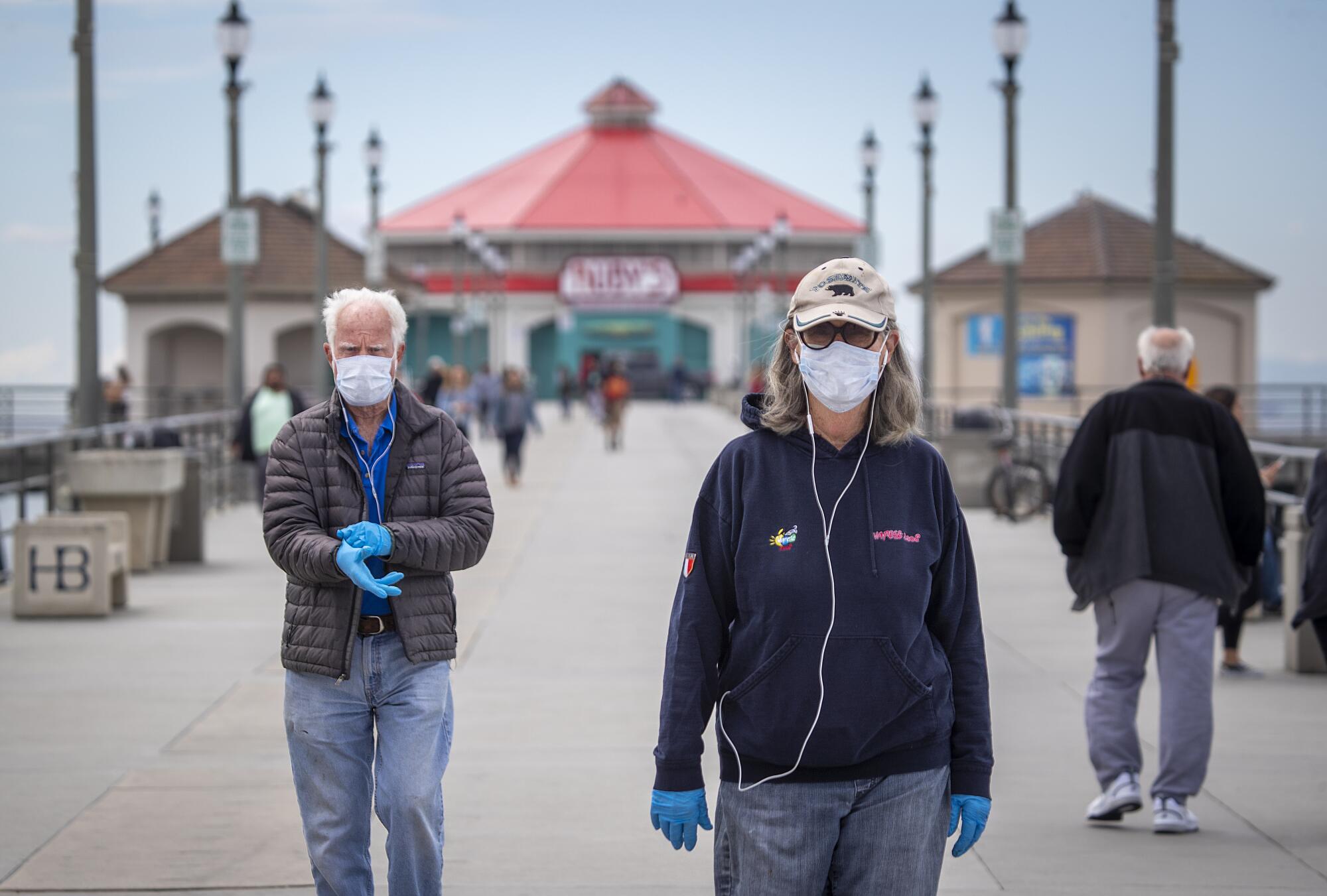 Dallas Weaver, 79, and his wife, Janet Weaver, 75, of Huntington Beach, return from a walk on the Huntington Beach pier amid the coronavirus pandemic.