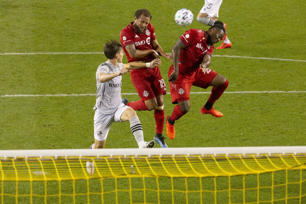 Toronto FC midfielder Nick DeLeon, center, gets between Montreal Impact's Jukka Raitala, left, and TFC's Ayo Akinola only to send his header wide during the second half of an MLS soccer match in Toronto, Ontario, Tuesday, Sept. 1, 2020. (Chris Young/The Canadian Press via AP)