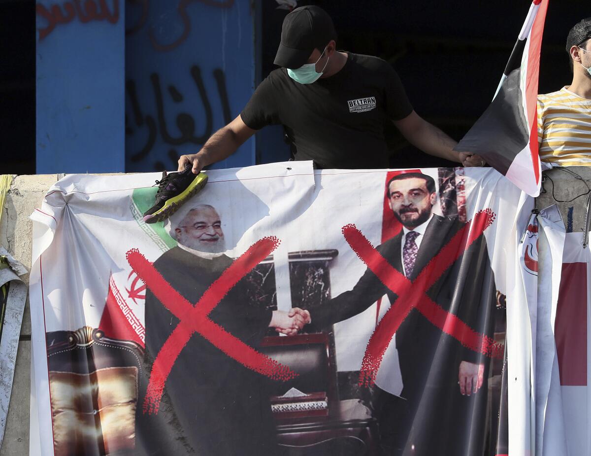 A defaced poster featuring Iranian President Hassan Rouhani, left, and Iraqi official Mohammed al-Halbousi is displayed during ongoing protests in Baghdad.