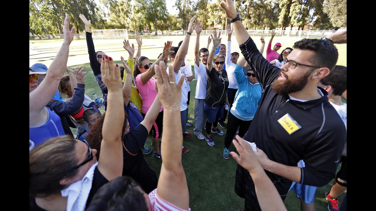 Cal State Northridge kinesiology graduate student Christopher Balam, right, leads a group in a cheer after an exercise session at Lanark Park in Canoga Park. Many of the class participants had never lifted a weight or jumped rope in their lives.