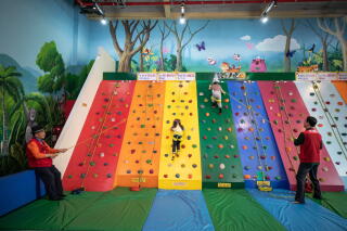 Children walk up a colorful rock-climbing slope indoors