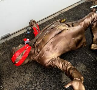 A bronze statue of President Trump with its broken head taped back together.