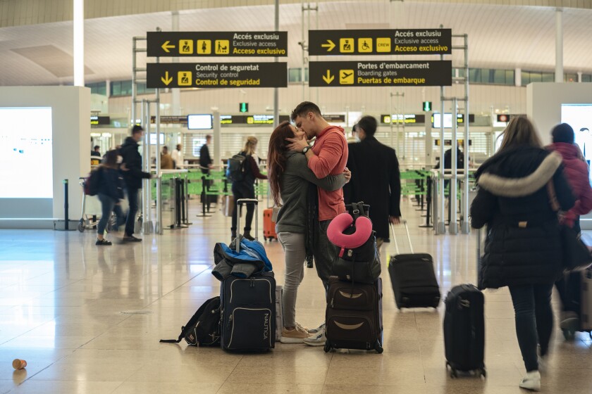 A couple kiss inside a terminal of the Barcelona Airport, Wednesday, Dec. 1, 2021. Health authorities in the Spanish capital have confirmed a second case of the omicron coronavirus variant in a 61-year-old woman who had returned from a trip to South Africa on Monday. Meanwhile lines have returned for those seeking vaccine shots in Portugal and Spain as they step up efforts to close the gap of the few residents still unvaccinated. (AP Photo/Joan Mateu Parra)