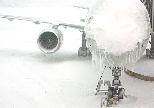 A Continental Airlines plane collects ice and snow, sitting near the concourse at Denver International Airport.
