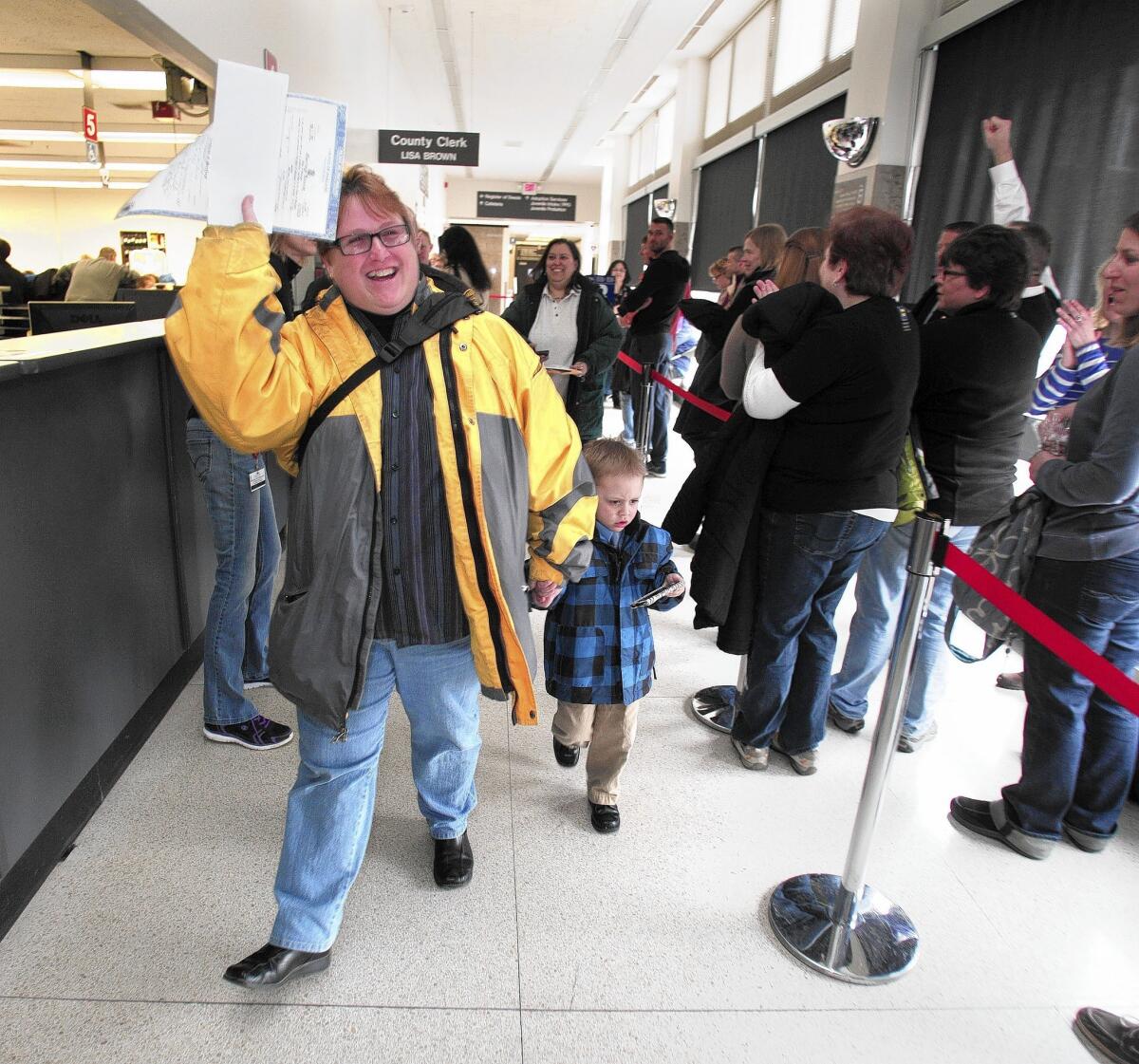 A woman shows off her marriage license at the Oakland County Courthouse in Pontiac, Mich., earlier this month. The federal government is recognizing Michigan's same-sex marriages even though further marriages are on hold pending a review.