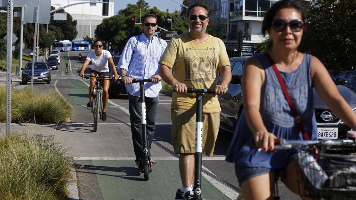 People on bikes and Bird scooters ride past a rally called, "A Day Without a Scooter" in front of City Hall in Santa Monica.