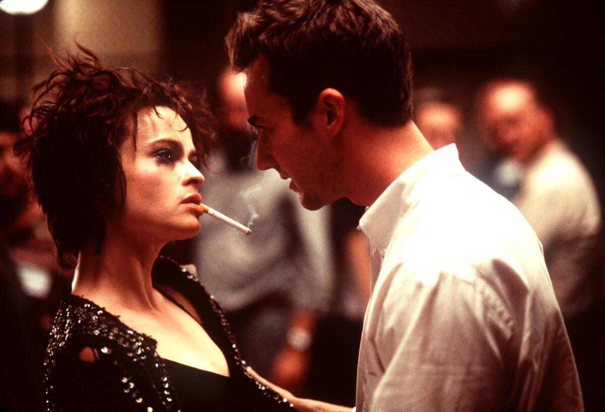 Helena Bonham Carter smokes and stares at Edward Norton as he holds her arms and talks to her in a 'Fight Club' scene