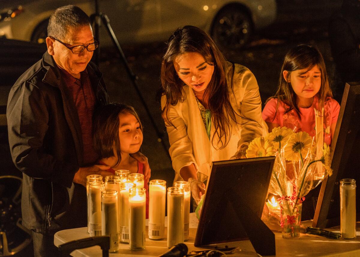 Cha Lee Xiong, father of shooting victim, Kou Xiong, Alina Xiong, 5, daughter of shooting victim, Kou Xiong, Hmong community advocate Paula Yang,and Alina Xiong,5,lf, Kou's niece, stand before a picture of Kou Xiong.