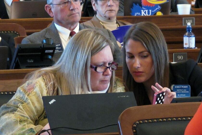 Kansas state Reps. Julie Menghini, left, and Emily Perry confer during a House debate on a bill dealing with gay marriage.