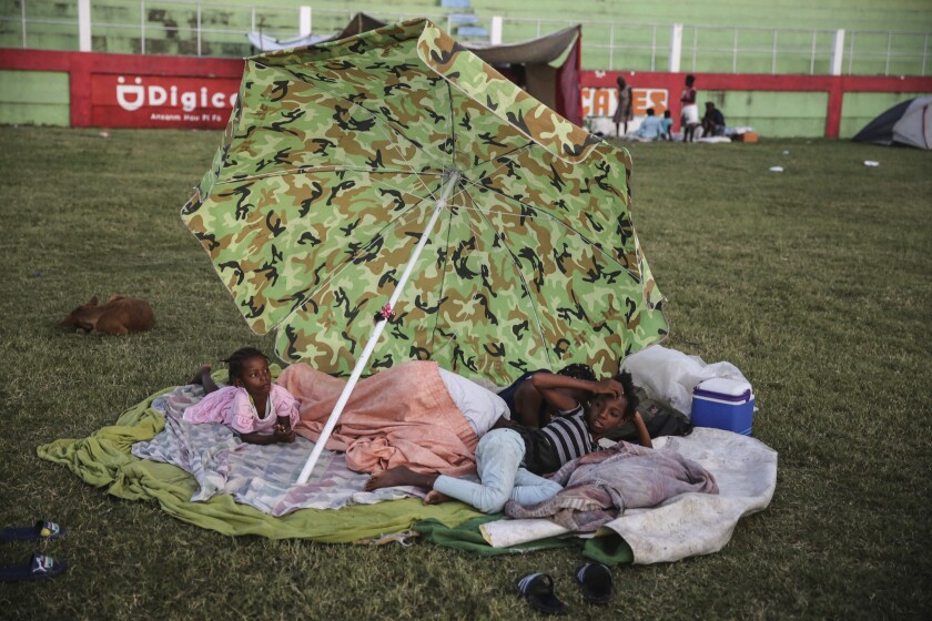 People rest after spending the night at a soccer field following Saturday´s 7.2 magnitude earthquake in Les Cayes, Haiti, Sunday, Aug. 15, 2021. (AP Photo/Joseph Odelyn)