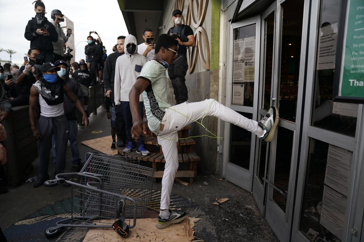 A person kicks in the door of a Whole Foods Market in the Fairfax District of Lo Angeles on Saturday