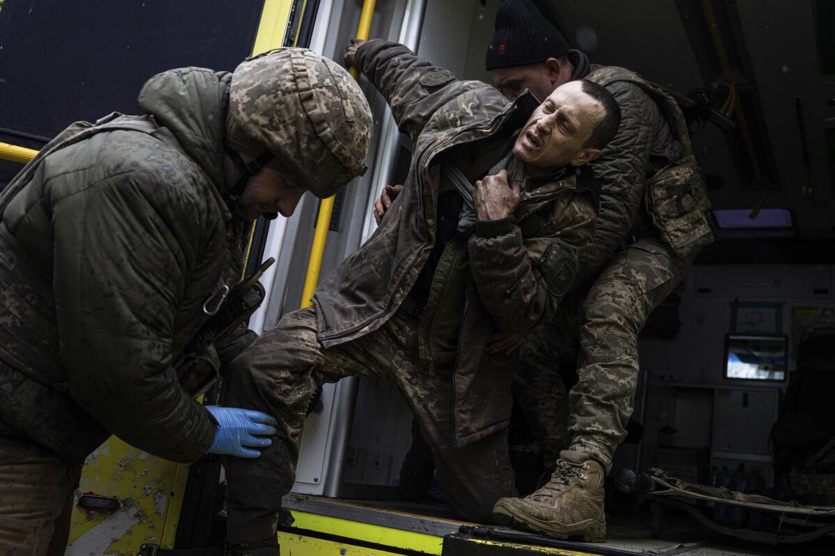 Médicos militares ucranianos ayudan a su camarada herido a salir de una ambulancia 