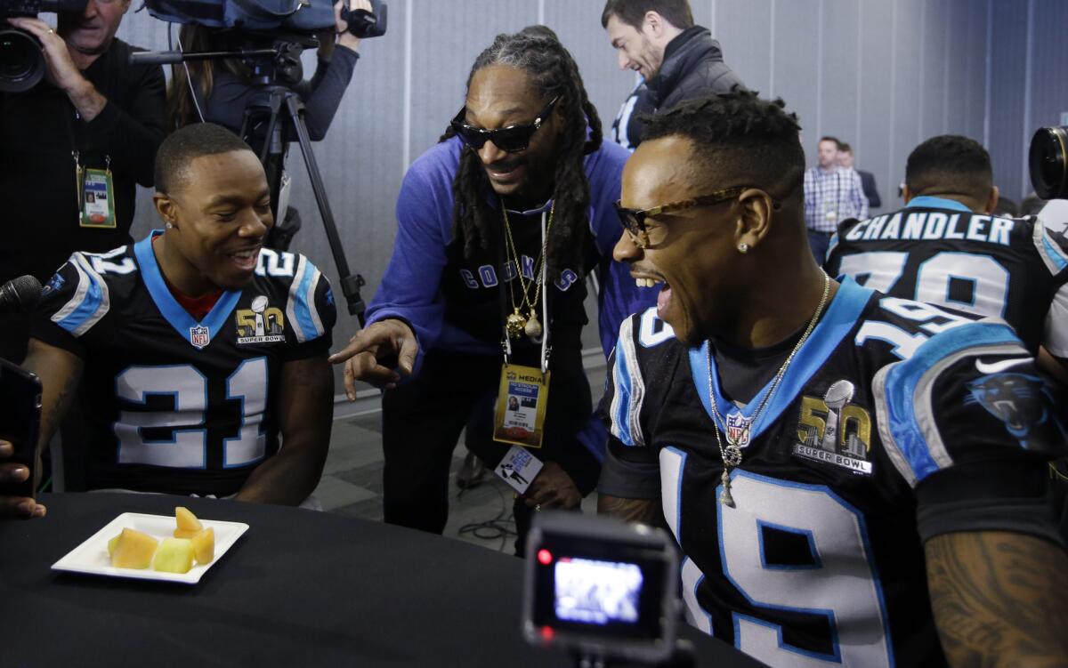 Snoop Dogg jokes with Carolina defensive back Teddy Williams, left, and wide receiver Ted Ginn Jr.