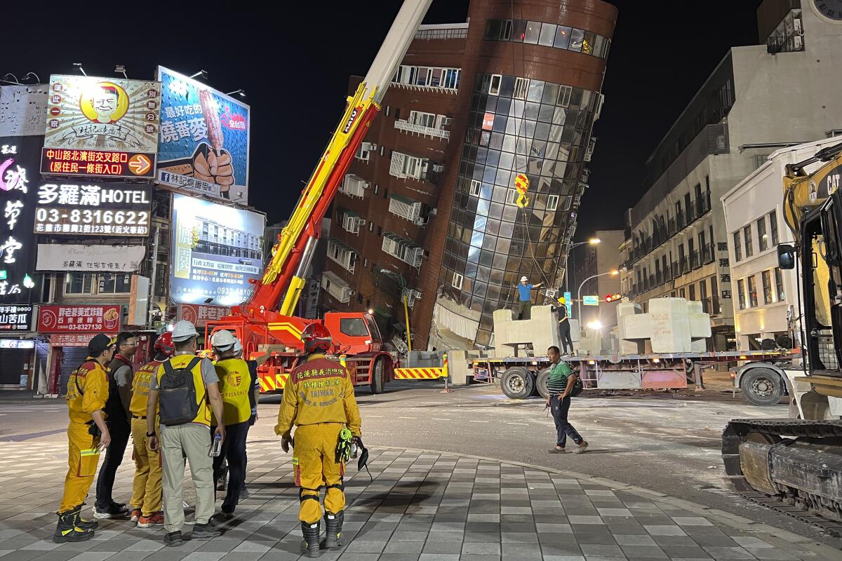 Rescue workers stand near a leaning building after an earthquake in Hualien, Taiwan.